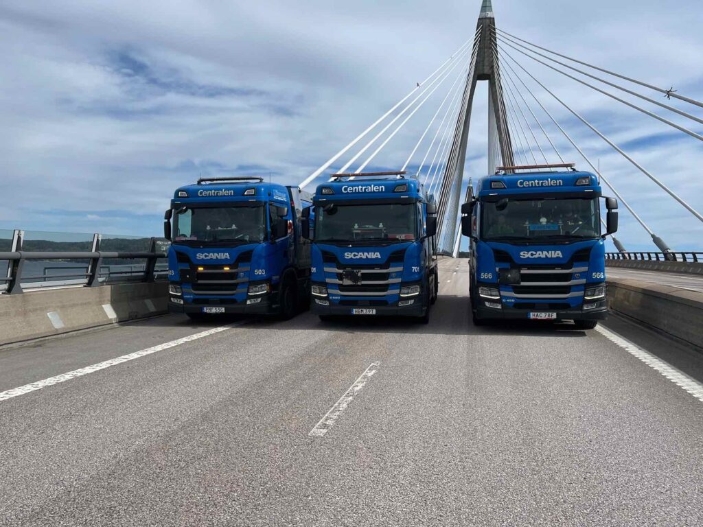 Tre blå Scania-lastbilar uppställda på Uddevallabron
