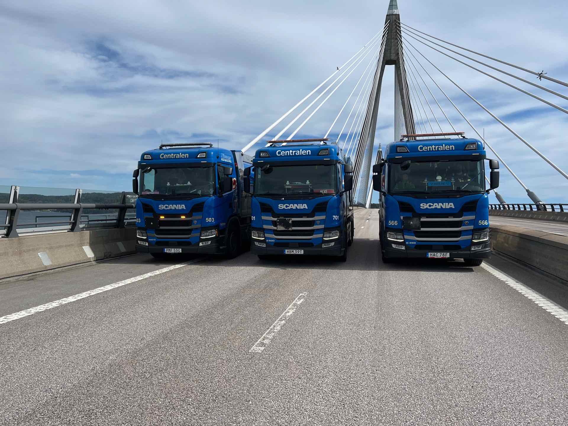 Tre blå Scania-lastbilar uppställda på Uddevallabron