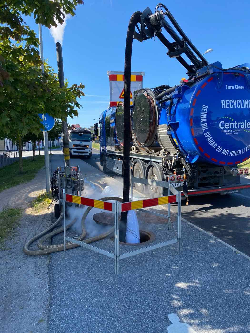 Avspärrad brunn med slang från spolbilen under en rörinspektion